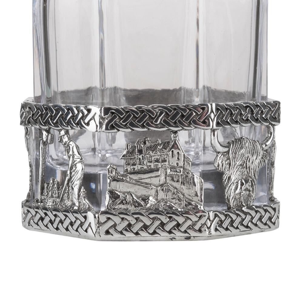 A glass decanter with a Pewter base showing a golfer and highland cow