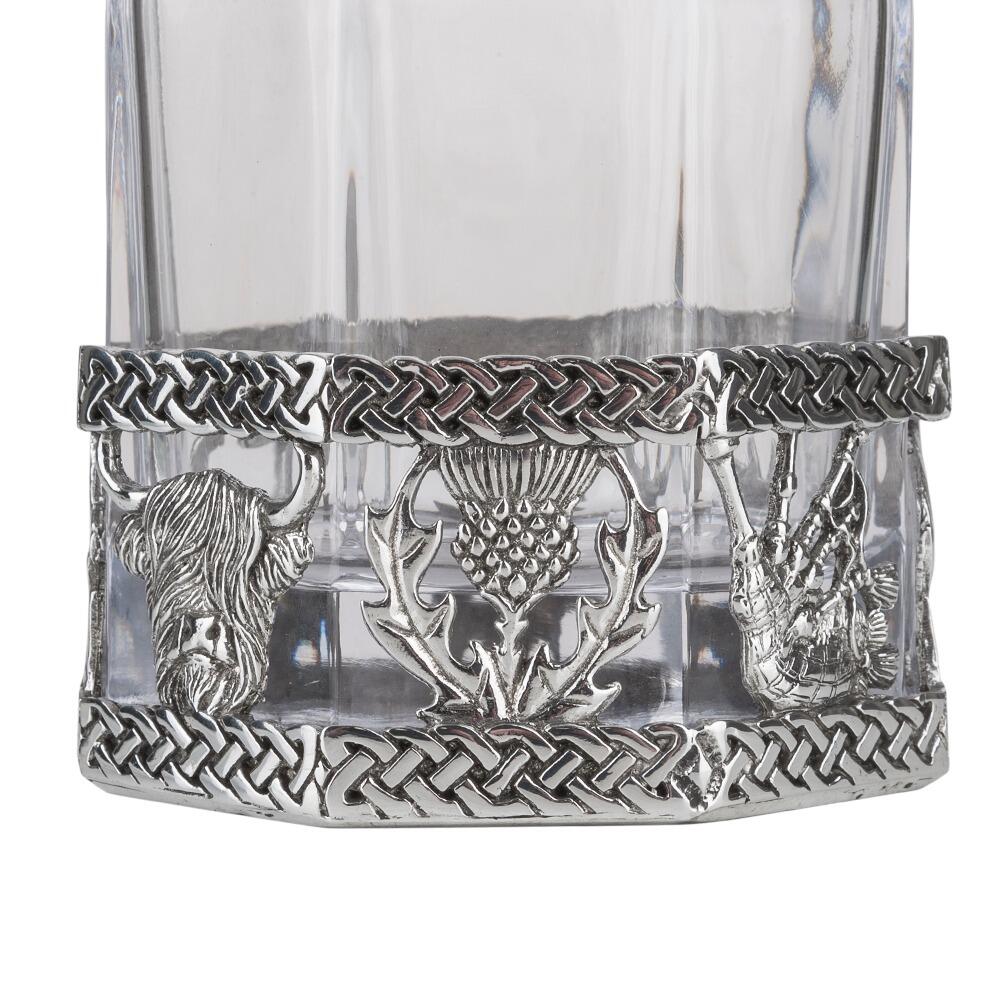 A glass decanter with a Pewter base showing a thistle