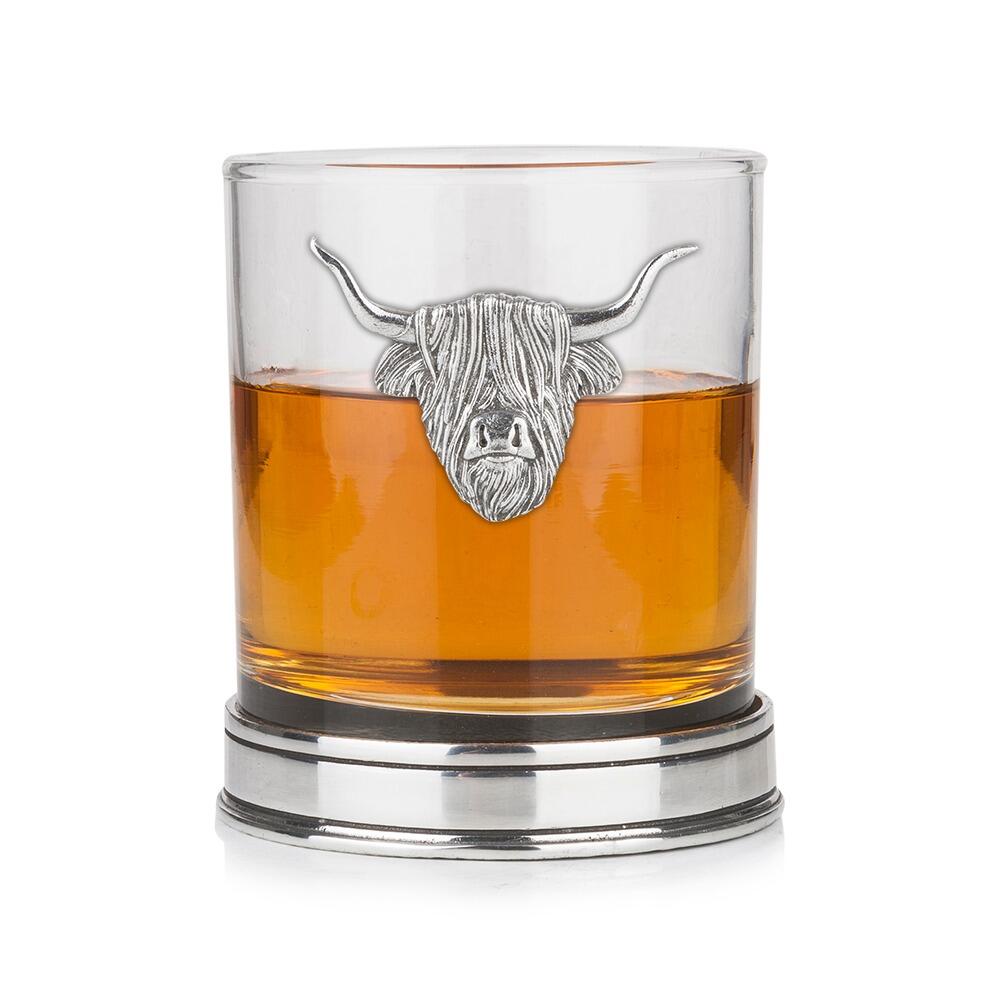 Whisky tumbler with pewter Highland Cow emblem and polished base, partially filled with amber liquid