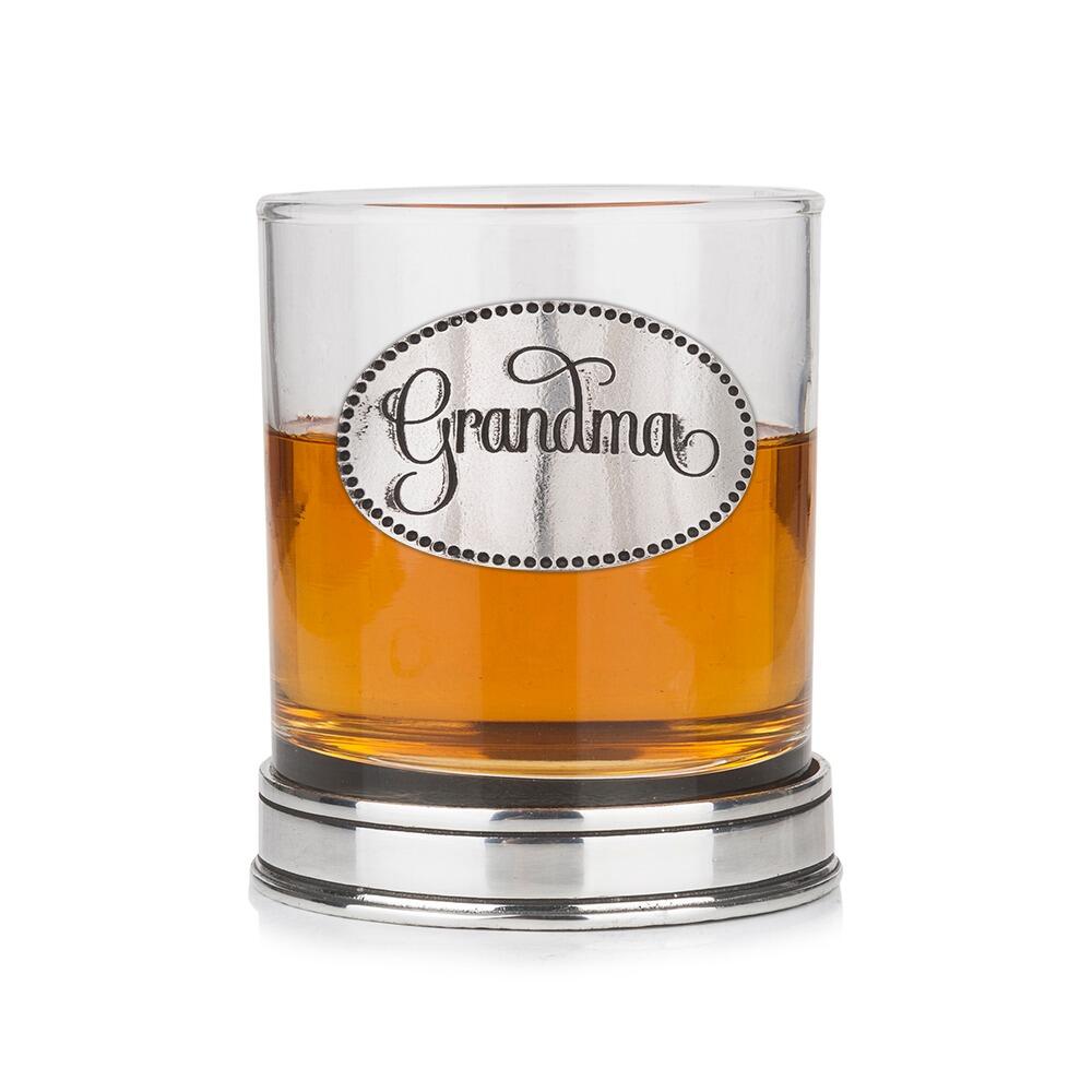 Whisky tumbler with pewter 'Grandma' badge and polished base, partially filled with amber liquid