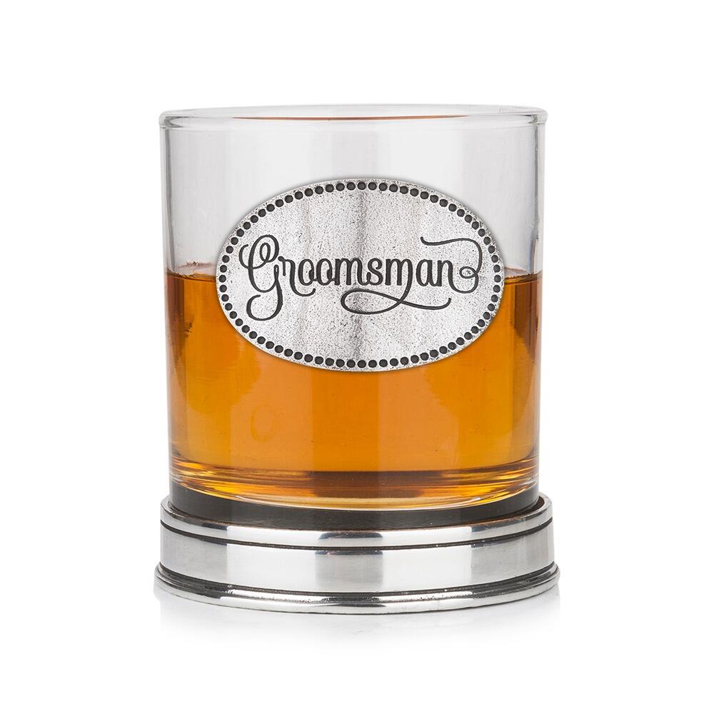 Whisky tumbler with pewter 'Groomsman' badge and polished base, partially filled with amber liquid