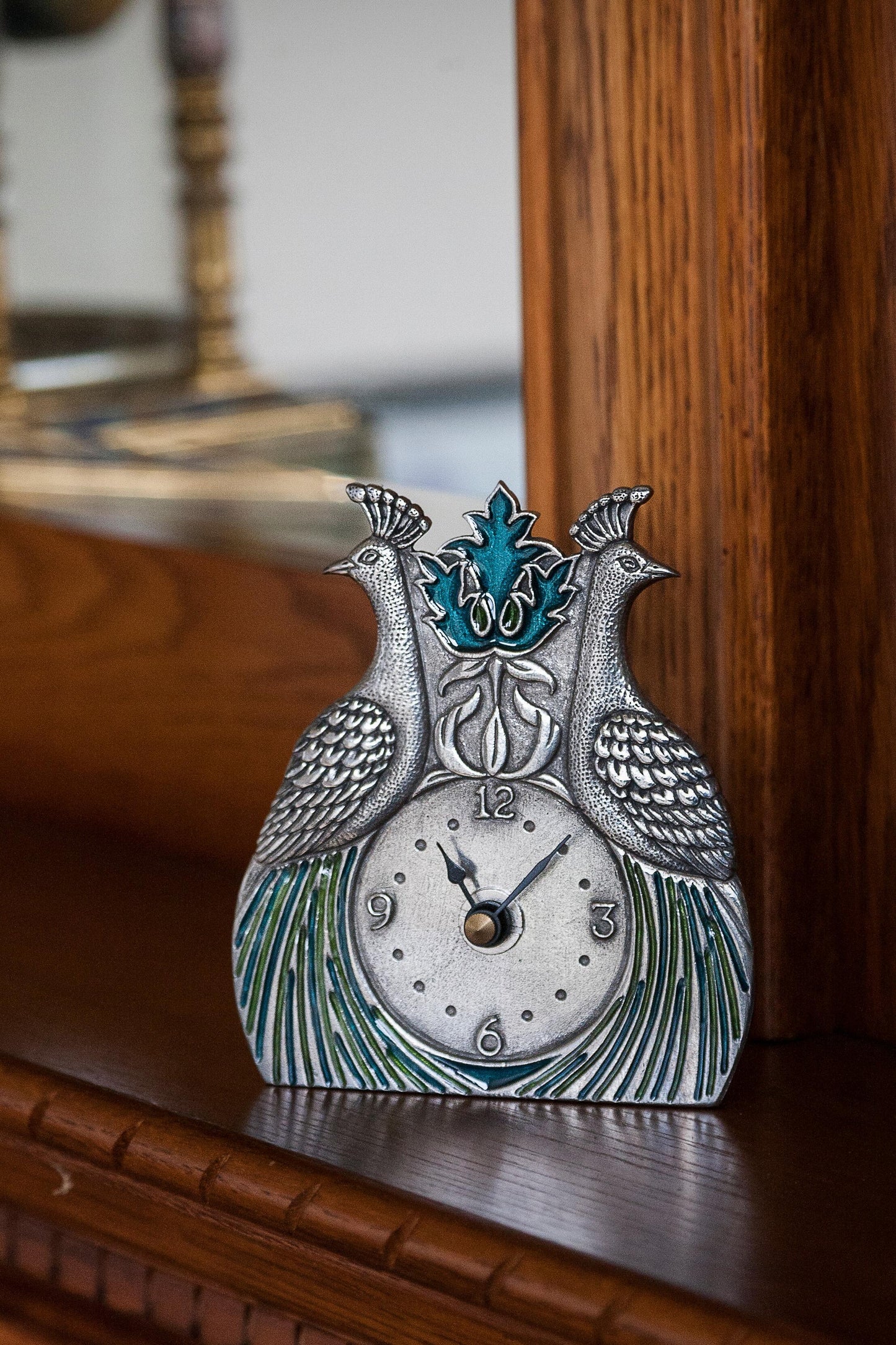 Pewter desk clock featuring two peacocks with blue and green enamelled feathers sitting on a desk