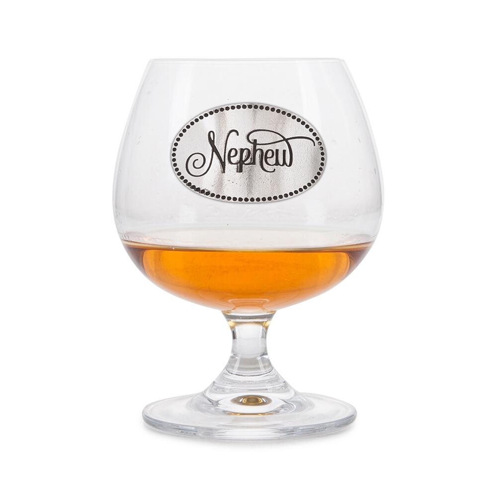 Elegant crystal brandy glass with pewter "Nephew" badge, partially filled with amber liquid