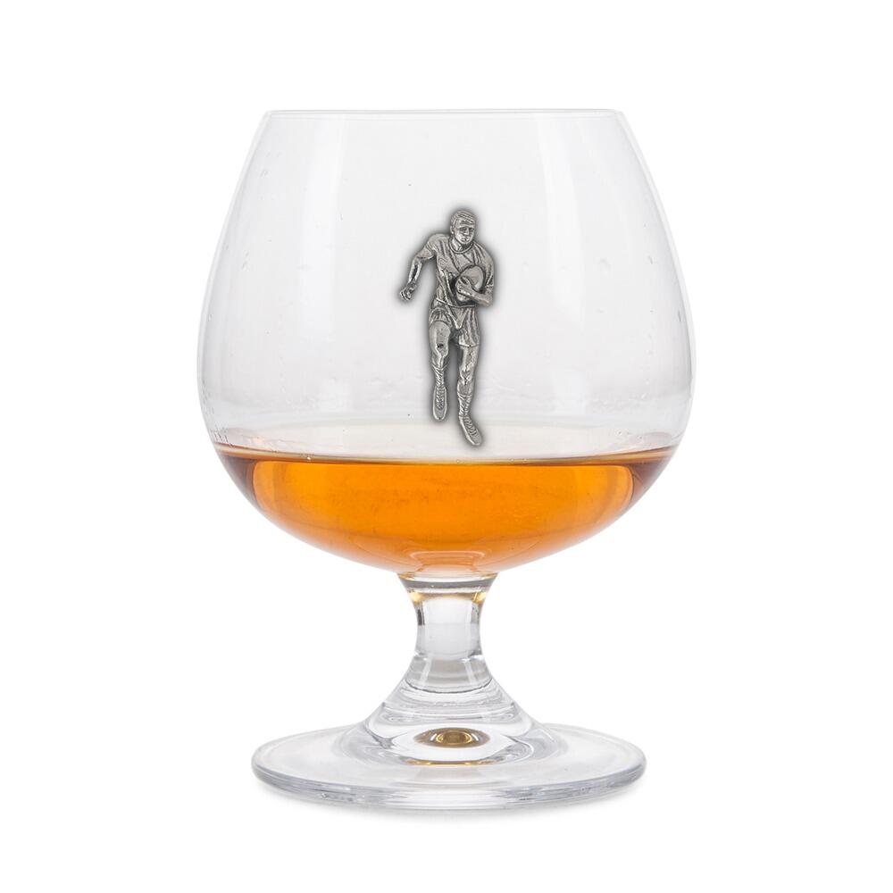 Crystal brandy glass with pewter rugby player emblem, partially filled with amber liquid