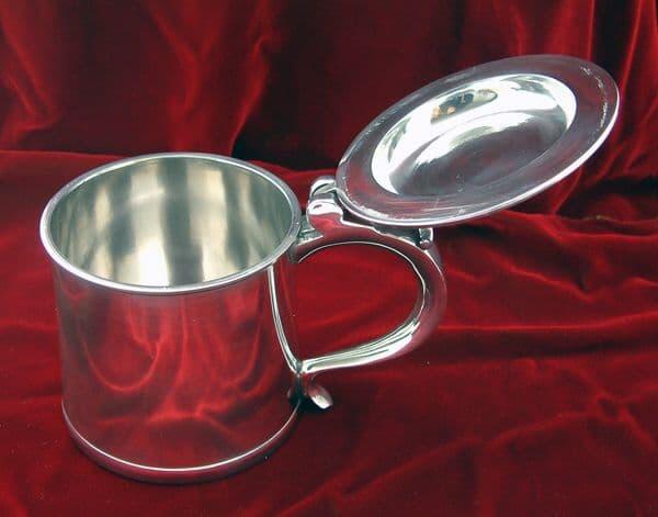 Polished stainless steel tankard with a hinged lid and a sturdy handle.