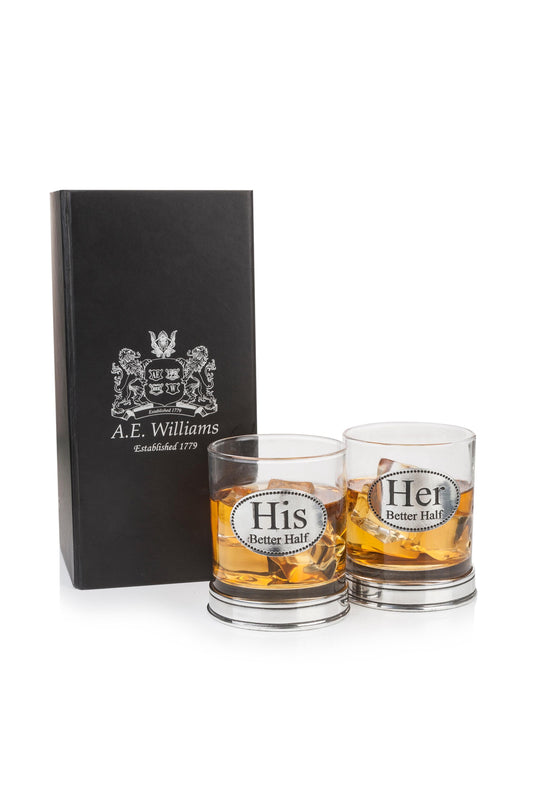 Set of two whisky tumblers with pewter "His Better Half" and "Her Better Half" badges and polished bases, partially filled with amber liquid