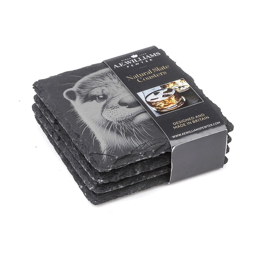 The top coaster features an engraved Otter design. A product label wraps around the stack, displaying the brand name, product type 'Natural Slate Coasters', and an image of a whiskey glass on a coaster. The label states 'Designed and Made in Britain' and includes the company website.