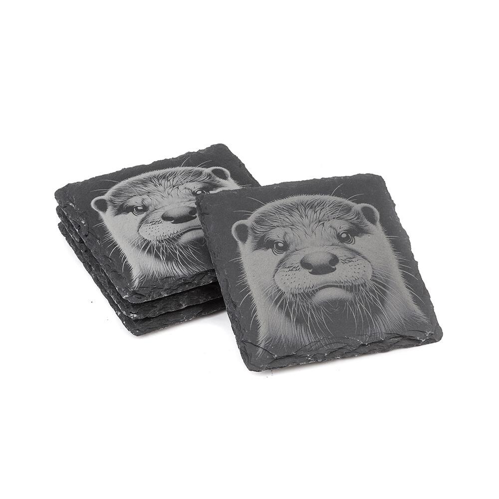 Natural slate coasters with etched otter design displayed in stacked arrangement