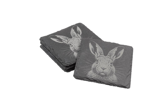 Two stacks of square slate coasters, each engraved with a detailed hare design.