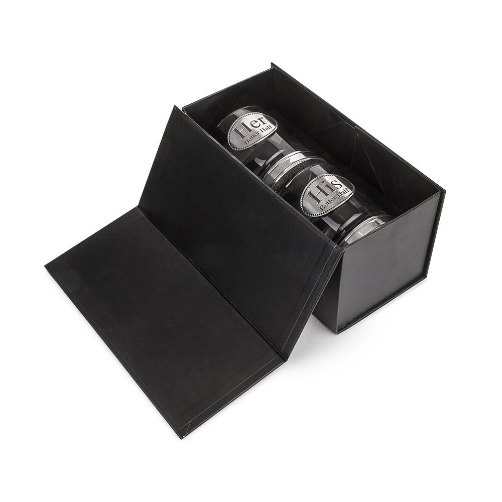 Set of two whisky tumblers with pewter "His Better Half" and "Her Better Half" badges and polished bases, partially filled with amber liquid In a Box