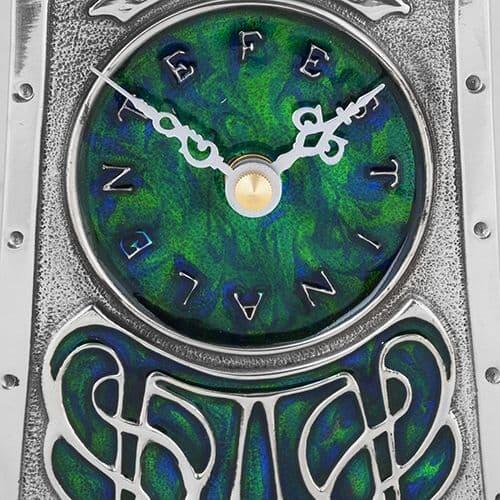Artisan pewter clock with Celtic design by Archibald Knox, featuring intricate patterns and an Arts & Crafts style.