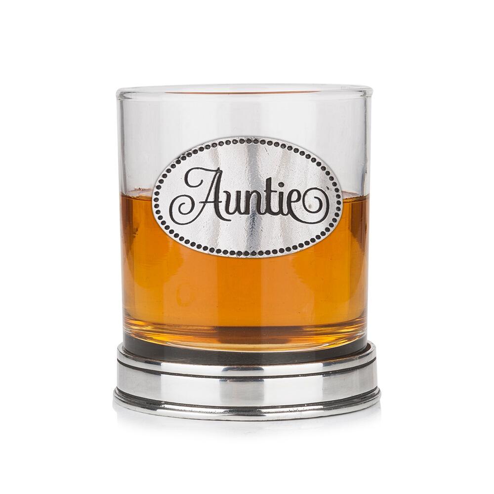 Whisky tumbler with pewter 'Auntie' badge and polished base, partially filled with amber liquid