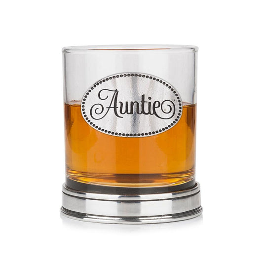 Whisky tumbler with pewter 'Auntie' badge and polished base, partially filled with amber liquid