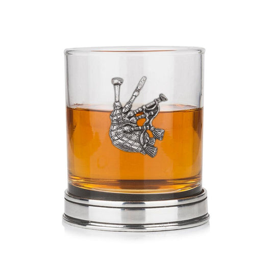 Whisky tumbler with pewter bagpipe emblem and polished base, partially filled with amber liquid