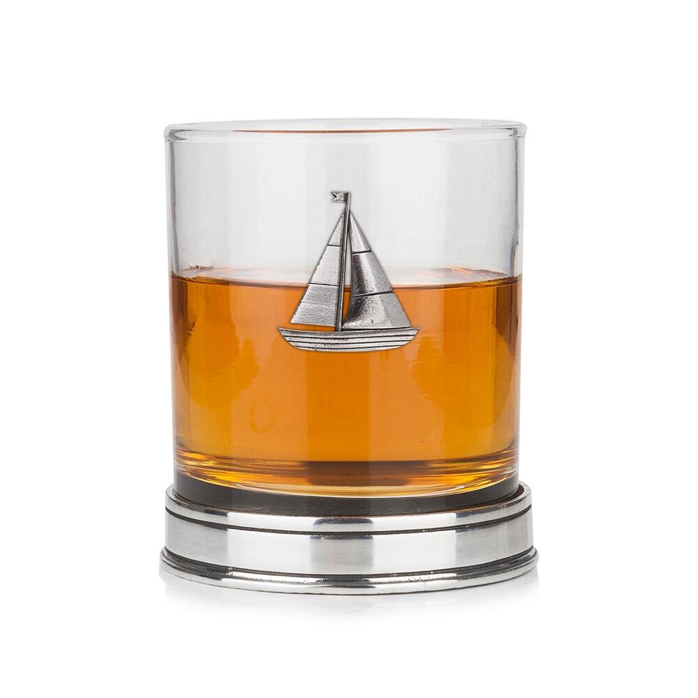 Whisky tumbler with pewter sailing boat emblem and polished base, partially filled with amber liquid