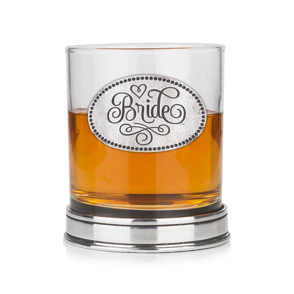 Whisky tumbler with pewter 'Bride' badge and polished base, partially filled with amber liquid