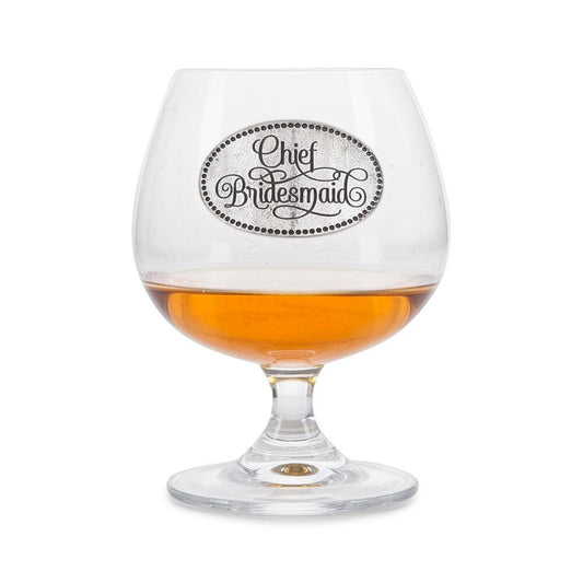Crystal brandy snifter with pewter "Chief Bridesmaid" badge, partially filled with amber liquid
