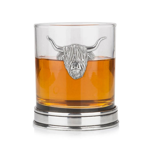 Whisky tumbler with pewter Highland Cow emblem and polished base, partially filled with amber liquid