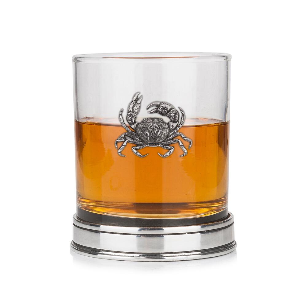 Whisky tumbler with pewter crab emblem and polished base, partially filled with amber liquid