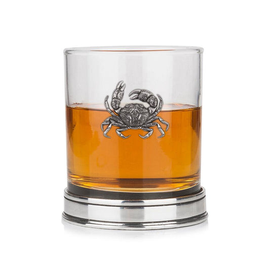 Whisky tumbler with pewter crab emblem and polished base, partially filled with amber liquid
