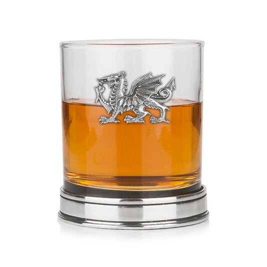 Whisky tumbler with pewter Welsh Dragon emblem and polished base, partially filled with amber liquid