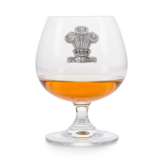Crystal brandy glass with pewter Welsh Feathers emblem, partially filled with amber liquid