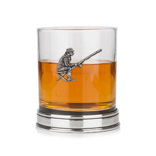Whisky tumbler with pewter fisherman emblem and polished base, partially filled with amber liquid