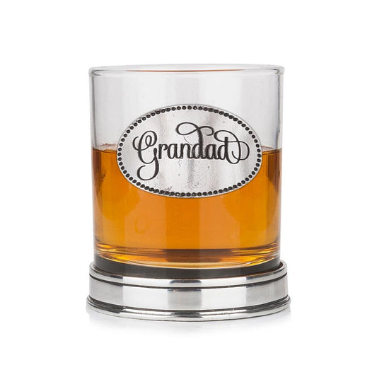 Whisky tumbler with pewter 'Grandad' badge and polished base, partially filled with amber liquid