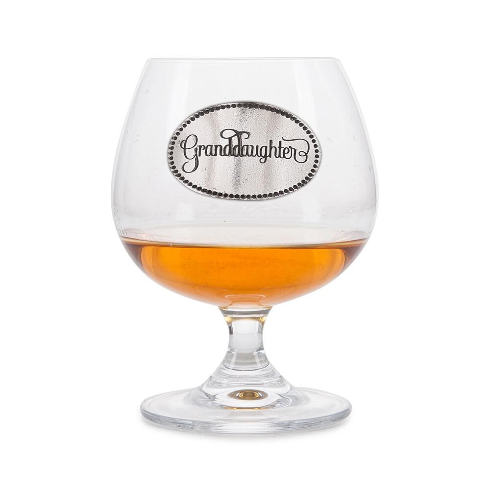 Crystal brandy glass with A E Williams pewter "Granddaughter" emblem, partially filled with amber liquid