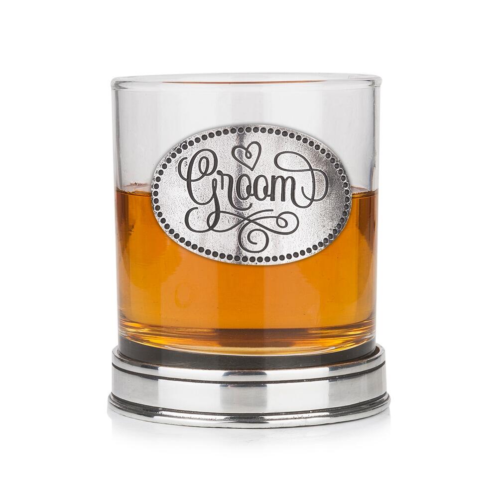 Whisky tumbler with pewter 'Groom' badge and polished base, partially filled with amber liquid