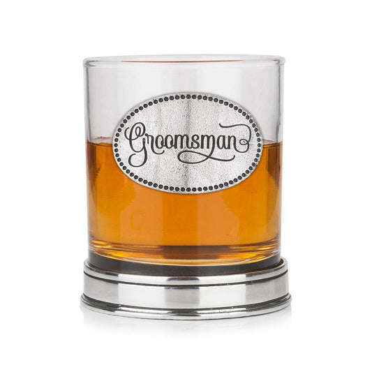 Whisky tumbler with pewter 'Groomsman' badge and polished base, partially filled with amber liquid