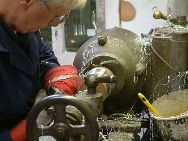 Craftsman using a lathe with metal shavings in a workshop