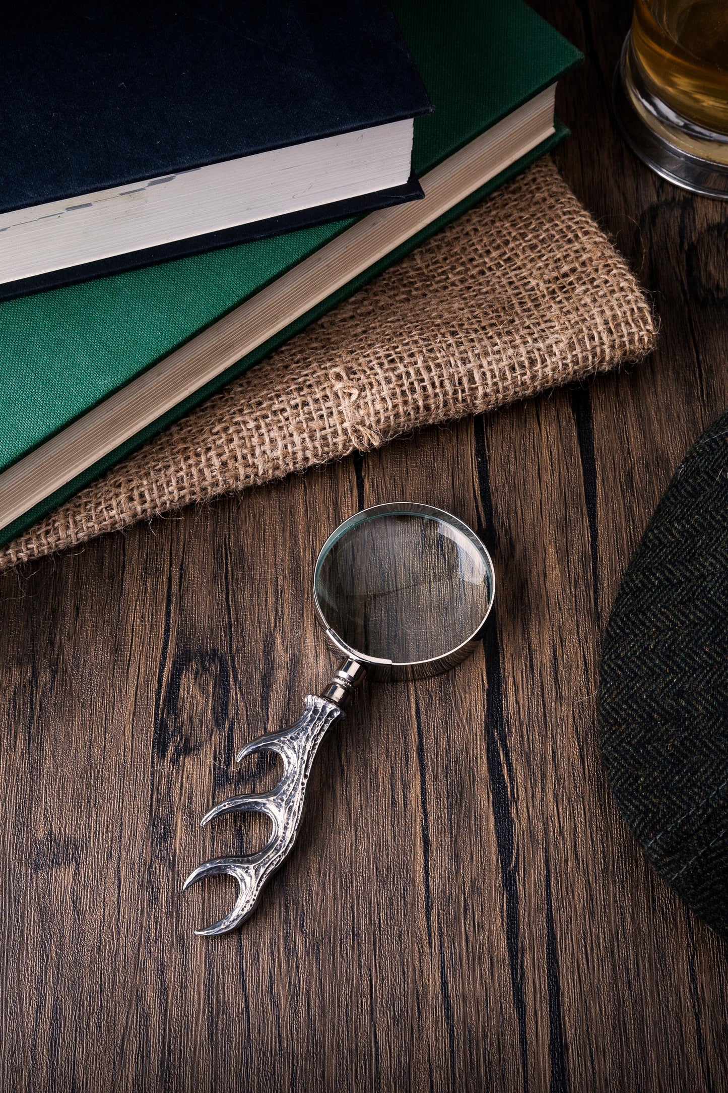 Pewter magnifying glass with detailed antler handle design on wooden surface