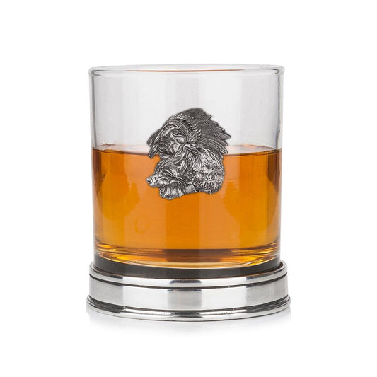 Whisky tumbler with pewter Native American and wolf emblem and polished base, partially filled with amber liquid