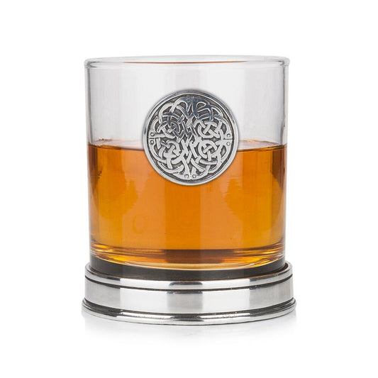 Whisky tumbler with pewter Never Ending Knot emblem and polished base, partially filled with amber liquid