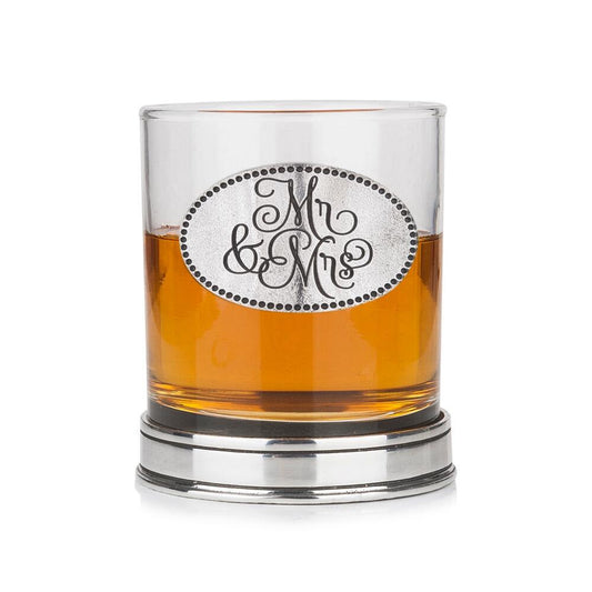 Whisky tumbler with pewter 'Mr & Mrs' badge and polished base, partially filled with amber liquid