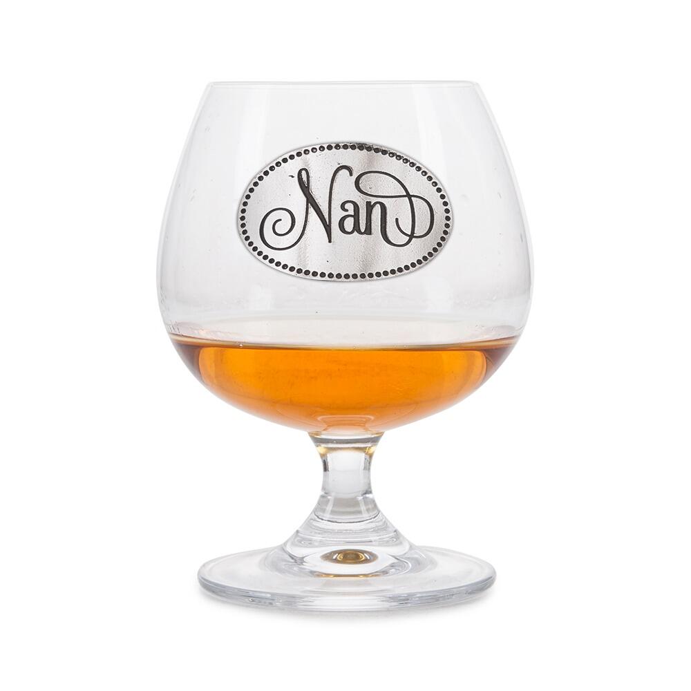 Elegant crystal brandy glass with pewter "Nan" badge, partially filled with amber liquid