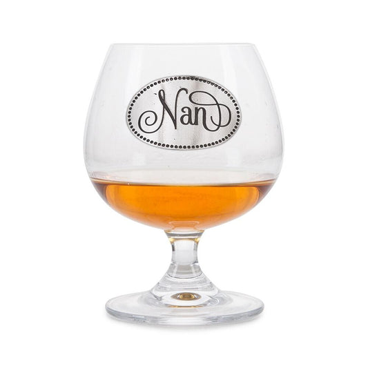 Elegant crystal brandy glass with pewter "Nan" badge, partially filled with amber liquid