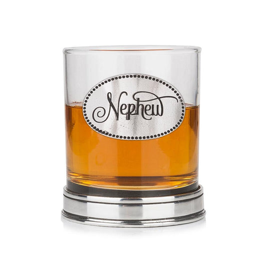 Whisky tumbler with pewter 'Nephew' badge and polished base, partially filled with amber liquid