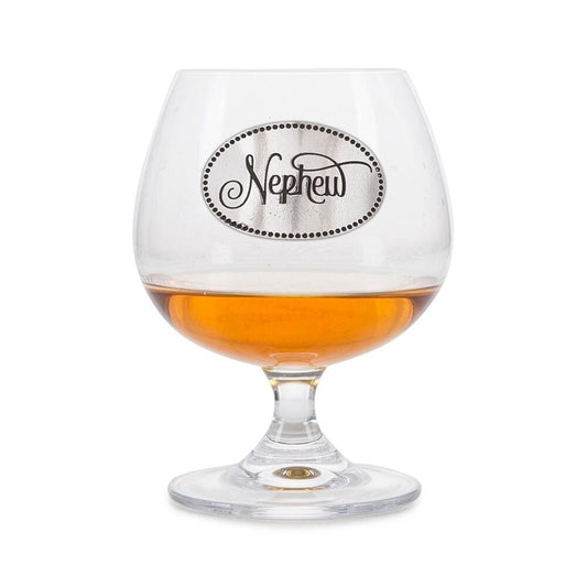 Elegant crystal brandy glass with pewter "Nephew" badge, partially filled with amber liquid
