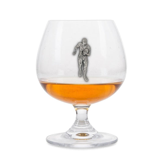 Crystal brandy glass with pewter rugby player emblem, partially filled with amber liquid