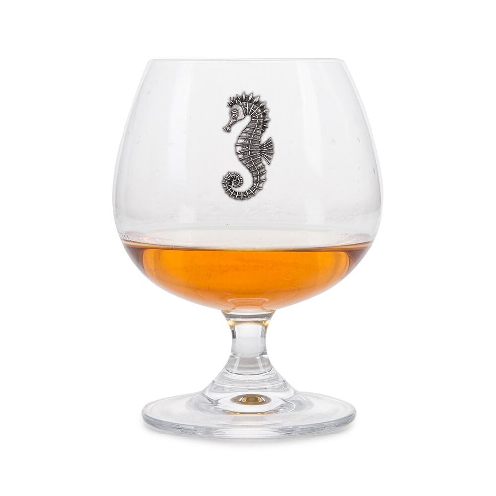 Crystal brandy glass with pewter seahorse emblem, partially filled with amber liquid
