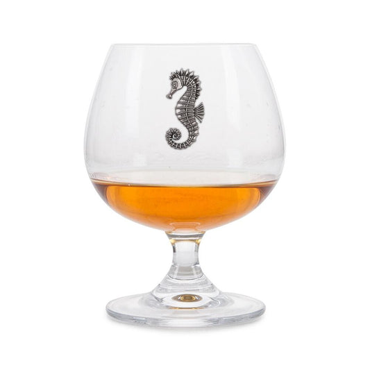 Crystal brandy glass with pewter seahorse emblem, partially filled with amber liquid