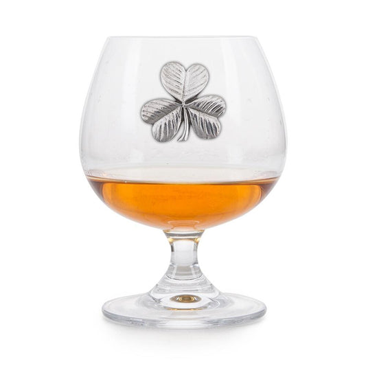 Crystal brandy glass with enamelled pewter shamrock emblem, partially filled with amber liquid