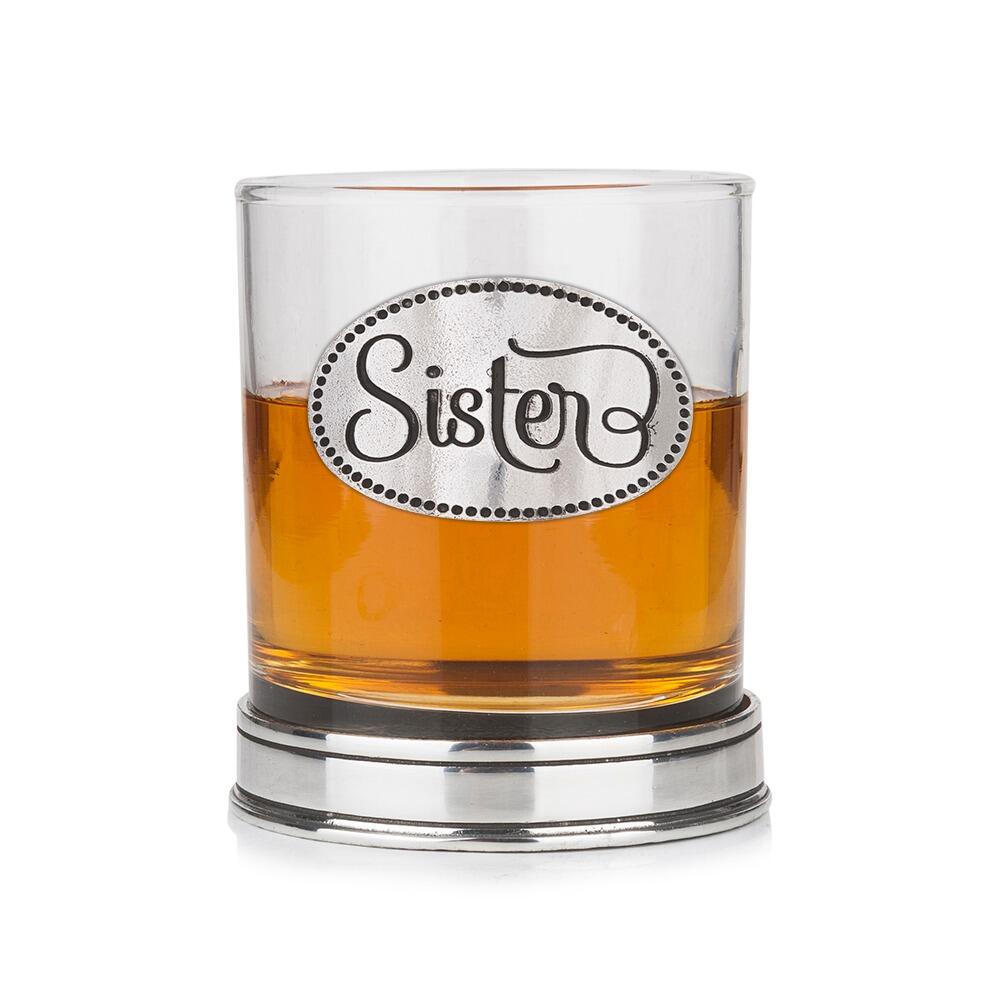 Whisky tumbler with pewter 'Sister' badge and polished base, partially filled with amber liquid