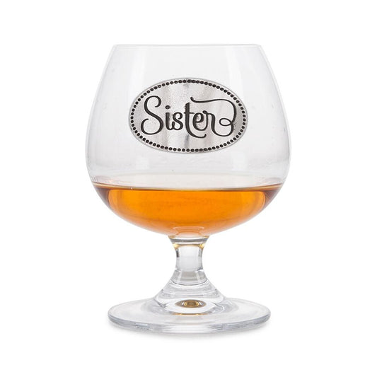 Crystal brandy glass with pewter 'Sister' badge, partially filled with amber liquid