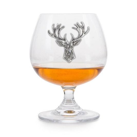 Crystal brandy glass with pewter stag badge, partially filled with amber liquid