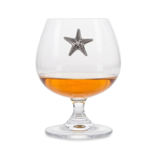 Crystal brandy glass with pewter starfish badge, partially filled with amber liquid