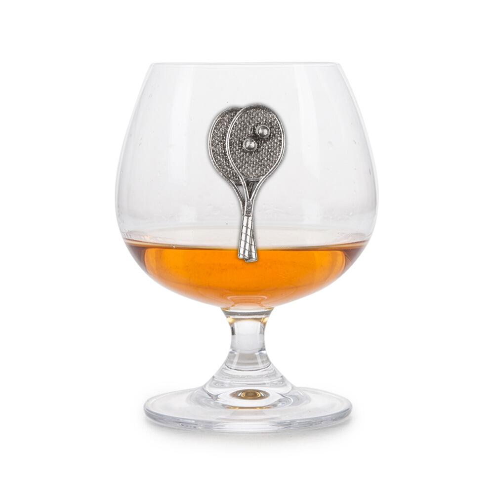 Crystal brandy glass with pewter tennis rackets emblem, partially filled with amber liquid