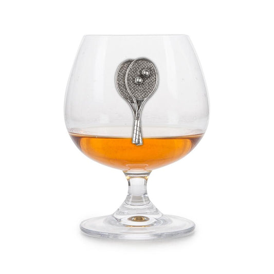 Crystal brandy glass with pewter tennis rackets emblem, partially filled with amber liquid